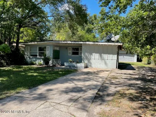 a front view of a house with garden and trees