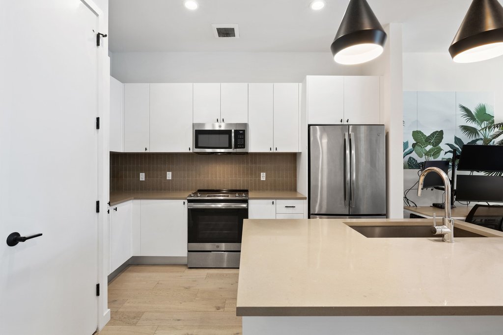 800 Embassy Drive, Unit 413 Austin, TX 78702 - Photo 3 of 27 Kitchen with stainless steel appliances, white cabinets, light wood finished floors, backsplash, and recessed lighting