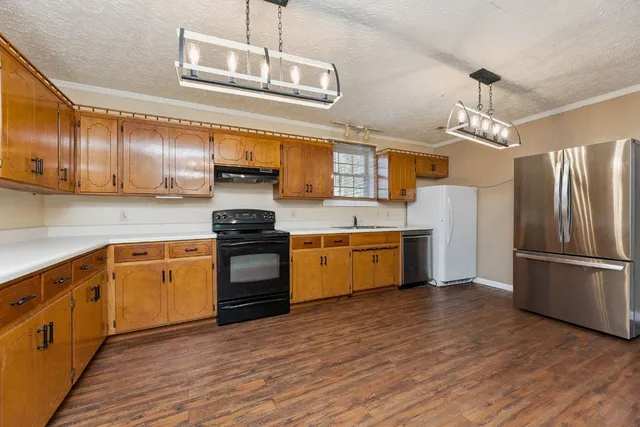 a kitchen with stainless steel appliances granite countertop a refrigerator a stove top oven a sink and dishwasher with wooden floor