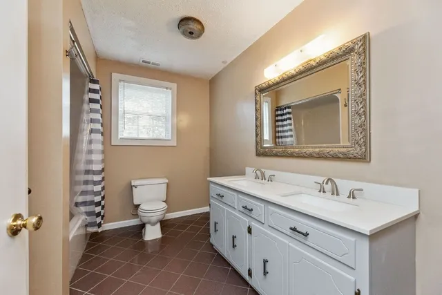 a bathroom with a double vanity sink mirror and toilet