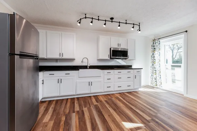 a kitchen with granite countertop a refrigerator and a stove top oven