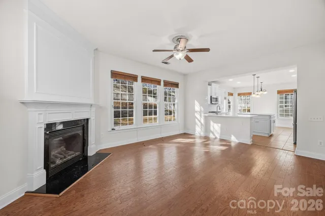 a view of an empty room with kitchen and fireplace