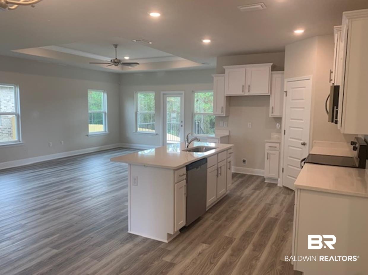 12904 Grand Rpds Road Fairhope, AL 36532 - Photo 27 of 34 Kitchen featuring a tray ceiling, white cabinets, appliances with stainless steel finishes, and a kitchen island with sink