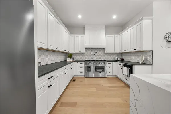 a kitchen with kitchen island granite countertop a refrigerator a sink a stove and wooden floors