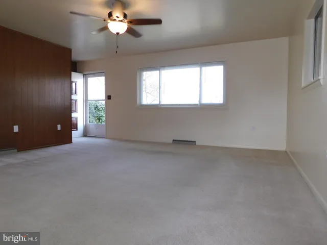 an empty room with a chandelier fan and windows