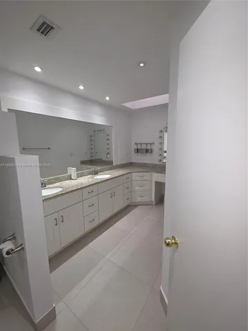 a large white kitchen with a sink a window and stainless steel appliances