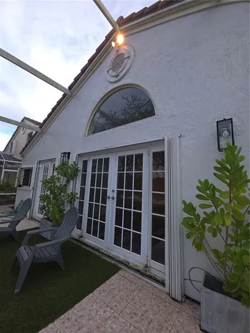 a view of a house with a large window and flower plants