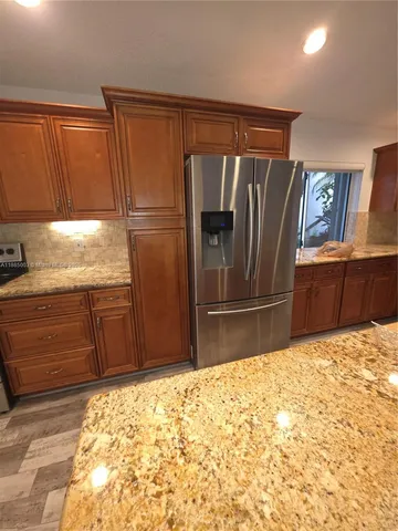 a kitchen with granite countertop a refrigerator and a sink