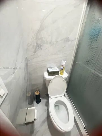 a white toilet sitting next to a shower