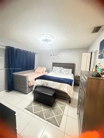 a bedroom with furniture and a refrigerator