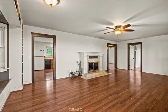a view of a livingroom with a fireplace a ceiling fan and wooden floor