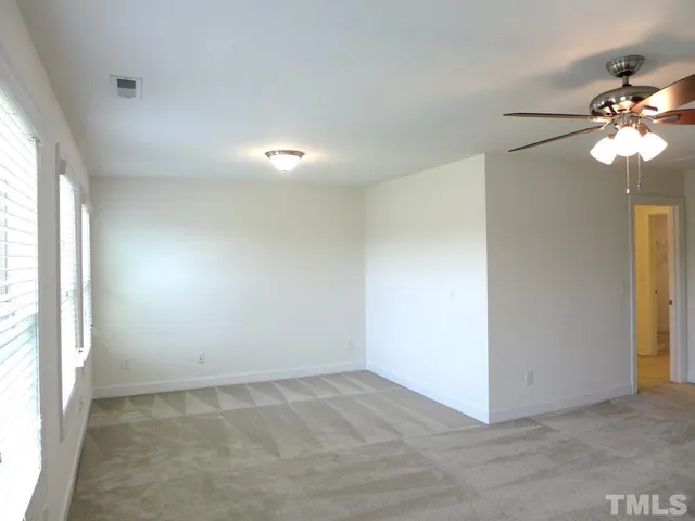 an empty room with windows and fan