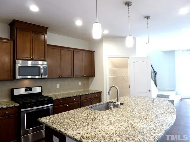 a kitchen with stainless steel appliances granite countertop a stove a sink and a microwave
