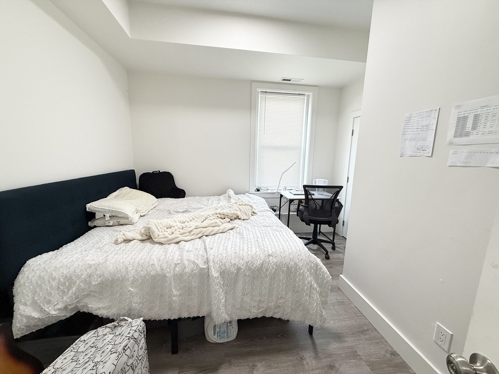 301-305 Dudley Street, Unit 2 Boston, MA 02119 - Photo 4 of 10 a bed sitting in a bedroom next to a window with chair and table