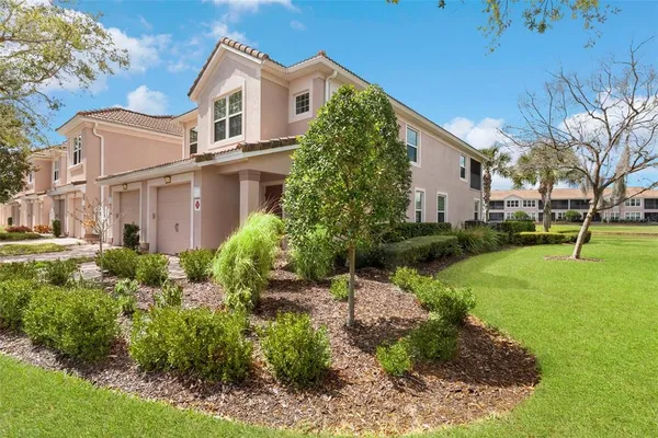 a view of a white house with a big yard and potted plants