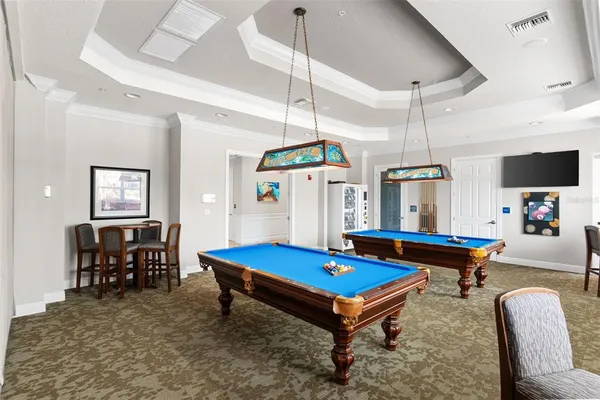 a living room with furniture pool table flat screen tv and windows