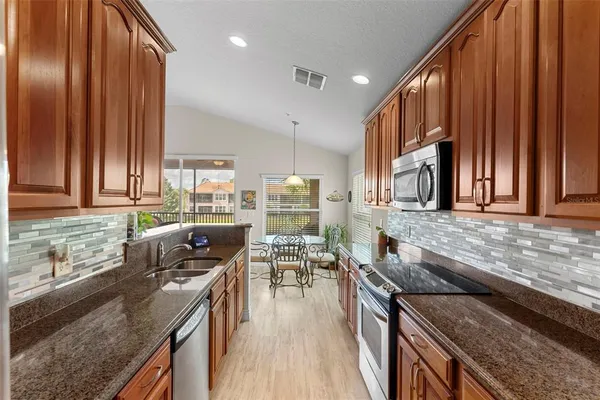 a kitchen with stainless steel appliances granite countertop a stove a sink and a microwave