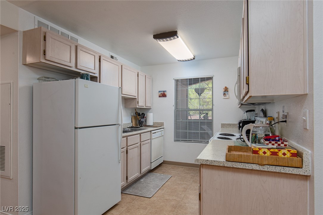 231 West Horizon Ridge Parkway, Unit 1126 Henderson, NV 89012 - Photo 7 of 33 Kitchen featuring white appliances, light countertops, light brown cabinetry, and light tile patterned floors