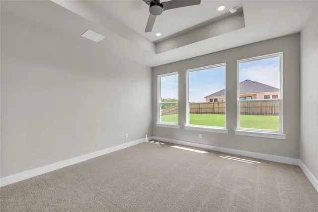 a view of an empty room with wooden floor ceiling fan and a window