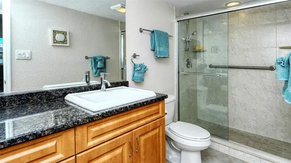 a bathroom with a granite countertop sink toilet and shower