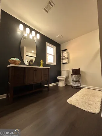 a living room with couches chairs and a large mirror with wooden floor