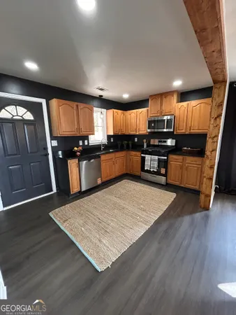 a kitchen with stainless steel appliances wooden floors wooden cabinets a refrigerator and microwave