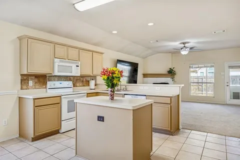 a kitchen with kitchen island granite countertop a sink cabinets and stainless steel appliances