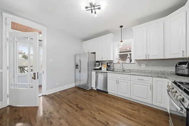 a kitchen with stainless steel appliances granite countertop a refrigerator sink and white cabinets