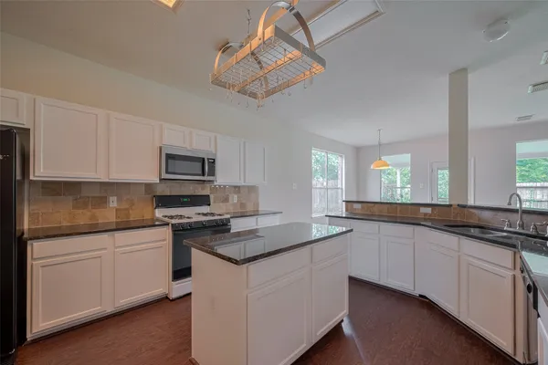 a kitchen with stainless steel appliances granite countertop a sink and dishwasher a stove top oven with white cabinets