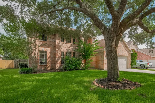 a view of a yard in front of a house with a large tree