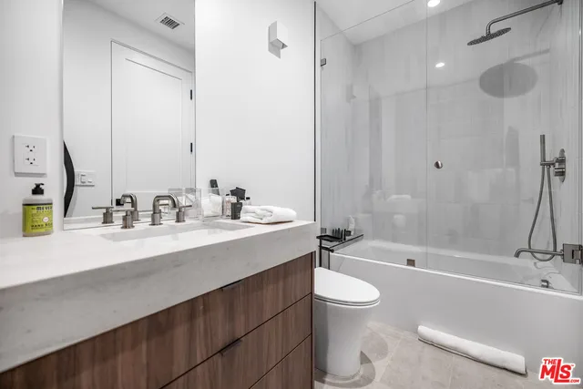 a bathroom with a granite countertop sink a toilet a mirror a bathtub and shower
