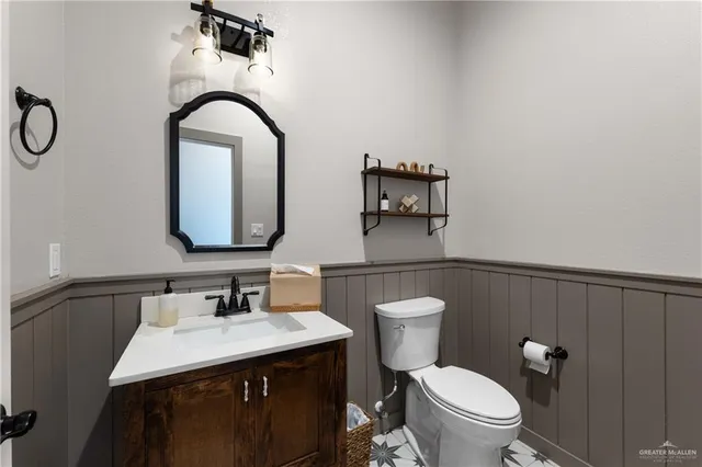a bathroom with a toilet sink vanity and mirror