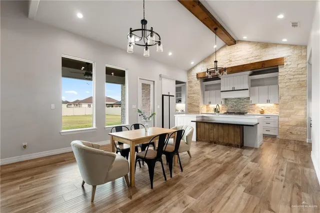 a kitchen with stainless steel appliances kitchen island granite countertop a table chairs and a wooden cabinets