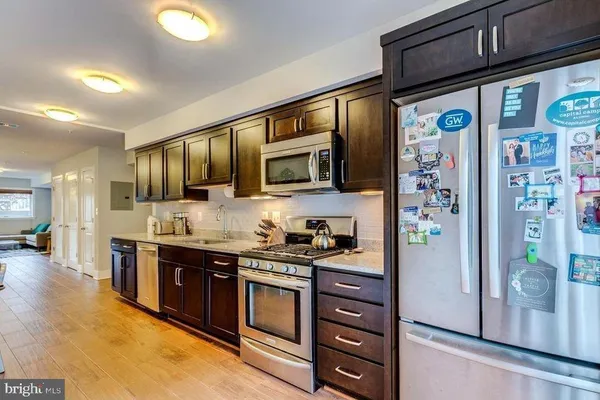 a kitchen with stainless steel appliances granite countertop a stove a refrigerator a dining table and chairs with wooden floor