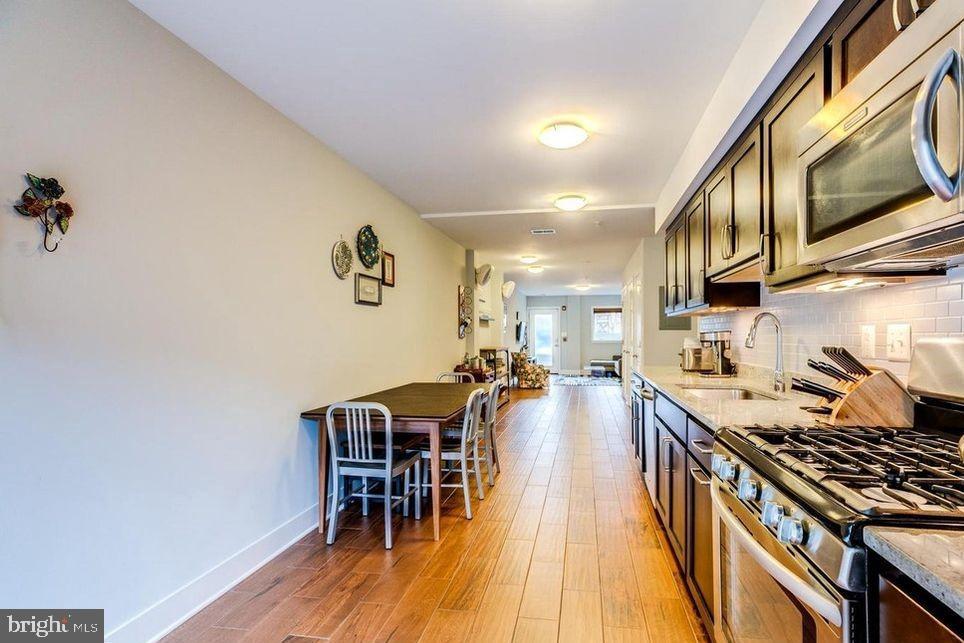 3465 14th Street Northwest, Unit A Washington, DC 20010 - Photo 16 of 28 a kitchen with stainless steel appliances granite countertop a stove a refrigerator a dining table and chairs with wooden floor