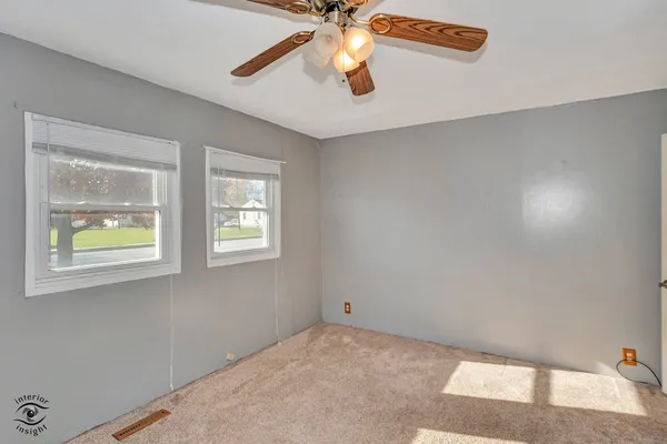 a view of an empty room with window and chandelier fan