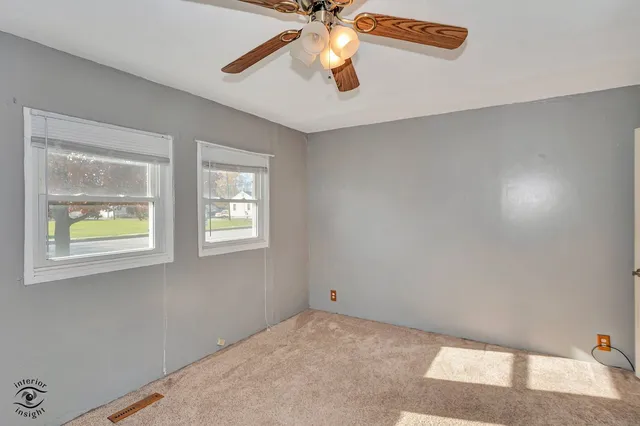 a view of an empty room with window and chandelier fan