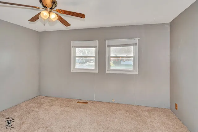 a view of an empty room with window and chandelier fan