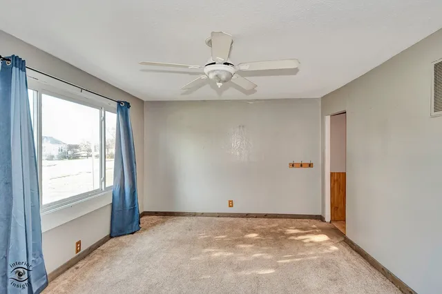 an empty room with windows and ceiling fan