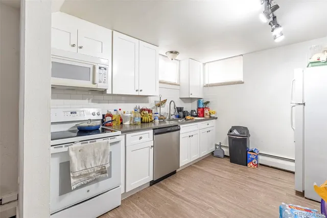 a kitchen with cabinets appliances wooden floor and a window