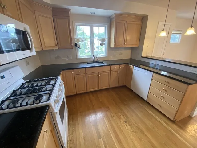 a kitchen with granite countertop a sink a stove and cabinets