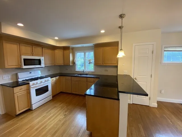 a kitchen with stainless steel appliances kitchen island granite countertop a stove a sink and a microwave