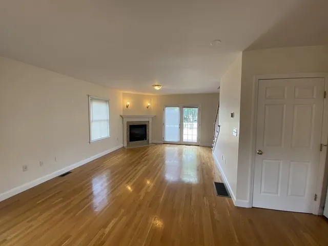 a view of empty room with wooden floor and fireplace