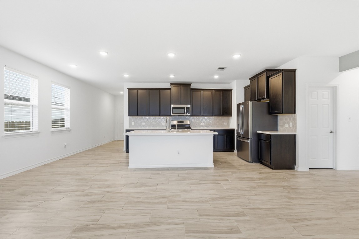 209 Thurman Holt Road Hutto, TX 78634 - Photo 31 of 32 a view of kitchen with stainless steel appliances kitchen island a sink dishwasher a refrigerator and a oven with wooden floor