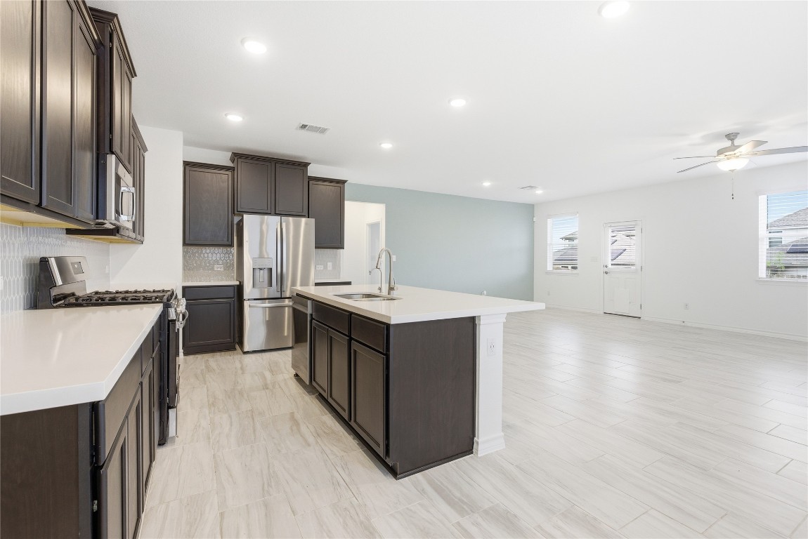 209 Thurman Holt Road Hutto, TX 78634 - Photo 32 of 32 a kitchen with stainless steel appliances granite countertop a stove top oven a refrigerator a sink and dishwasher with wooden floor