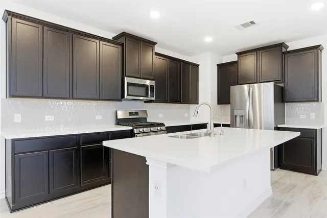 a view of kitchen with stainless steel appliances kitchen island a sink dishwasher a refrigerator and a oven with wooden floor