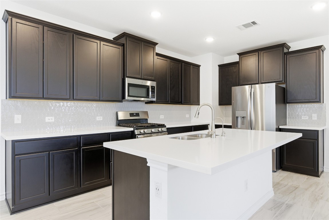 209 Thurman Holt Road Hutto, TX 78634 - Photo 21 of 32 a kitchen with stainless steel appliances a refrigerator stove microwave and sink