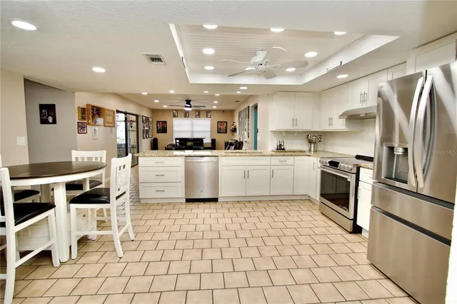 a kitchen with white cabinets stainless steel appliances and a dining table