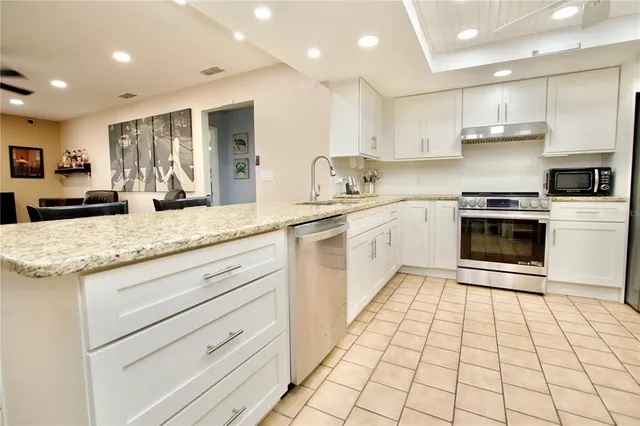 a kitchen with granite countertop white cabinets stainless steel appliances and sink