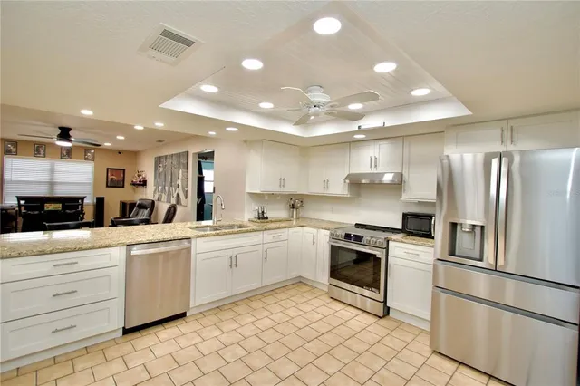 a kitchen with white cabinets stainless steel appliances and a sink